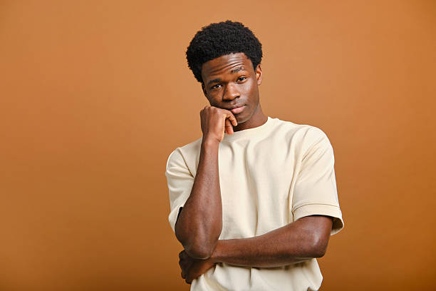 istock Young man with hand on chin looking pensive in studio shot 2207188822