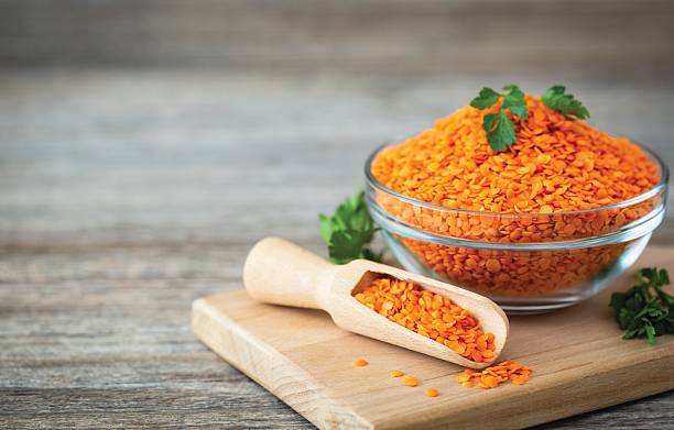 Red lentils in a bowl on the wooden background