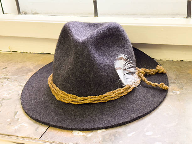 istock Gray felt hat with brown rope and feather on stone surface near window 2207188954