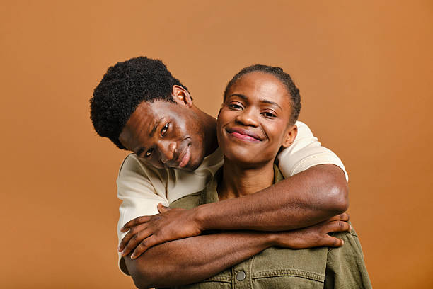 istock Young couple embracing and smiling at camera in studio 2207188960