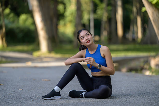 istock Sweating Asian athlete resting after intense training, seated on floor with contemplative gaze 2207189809
