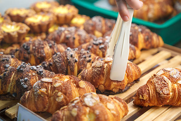 istock Baker Arranging Freshly Baked Pastries with Tongs 2207190615