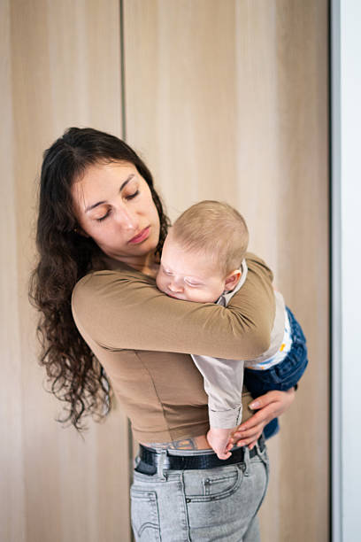 istock Young mother gently cradling her sleeping baby 2207192384
