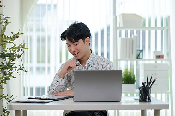 istock Young business working with laptop and reviewing reports in a modern office. 2207192711