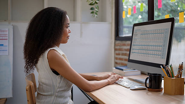 istock Professional woman working on financial spreadsheets in a modern office. 2207192959