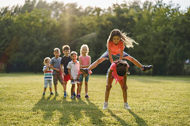 istock Happy children having fun while playing leapfrog game in public park 2207198775