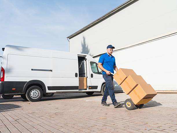 istock Delivery Man Transporting Boxes on Hand Truck from Van 2207198876
