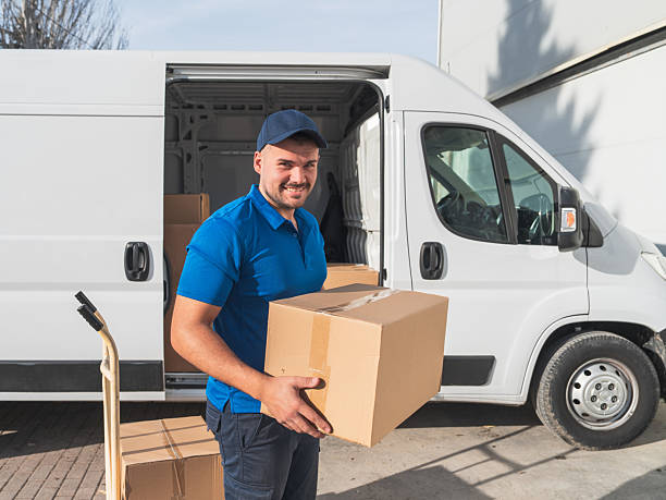 istock Smiling Delivery Man Holding Box Near Van 2207198878