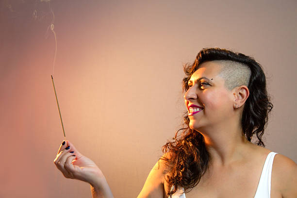 istock Half shaved hairstyle woman holding a lit incense stick. 2207199642