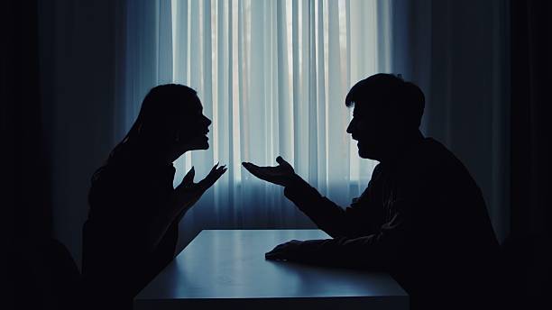 istock Silhouette of a Couple Arguing in Dimly Lit Room 2207200726