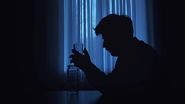 istock Silhouette of a Man Holding a Glass in Blue Light 2207200869