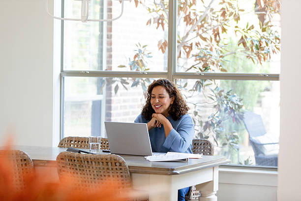 istock Smiling woman using laptop in bright home office 2207202078