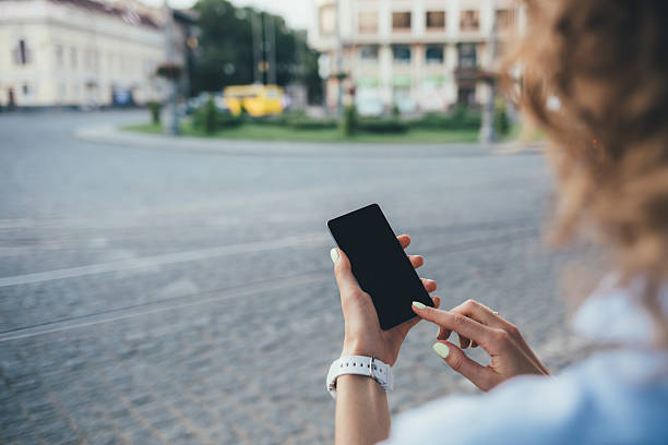 istock A woman is looking at her phone while standing on a street 2207202729