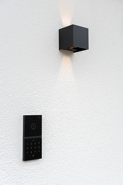 istock Modern Smart Doorbell and Wall Lamp on White Textured Wall 2207203240
