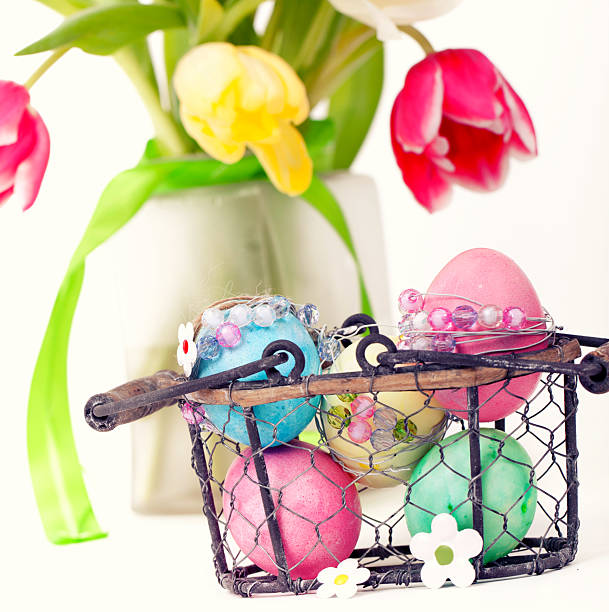 a vase with fresh tulips and a basket with colorful easter eggs