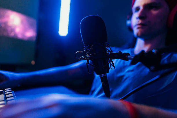 istock Gamer streaming and recording with professional microphone in a dark room 2207205930