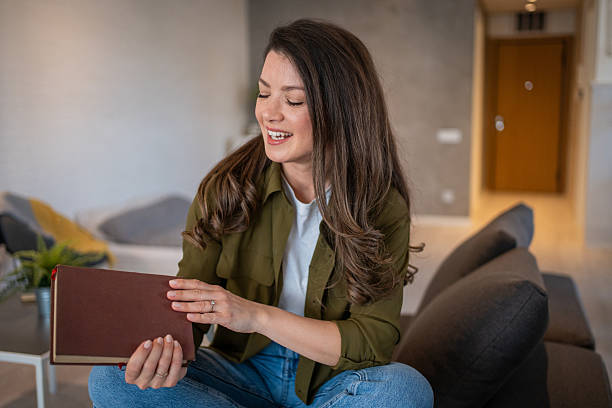 istock Young woman reading a book and smiling at home 2207206150