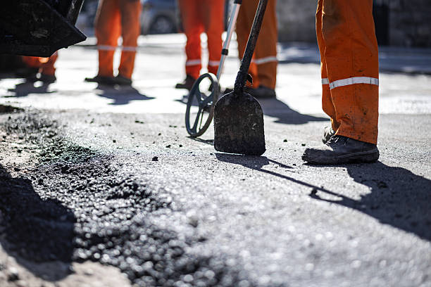 istock Construction workers repairing a road with shovels and equipment during daylight hours in an urban environment 2207209864