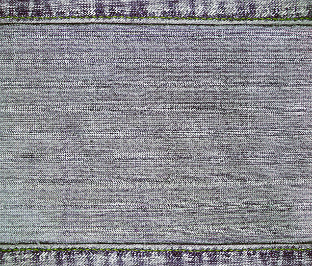 Gray denim background with a seamed frame. Grey color denim jeans fabric texture with decorative stitch border. Copy space for text