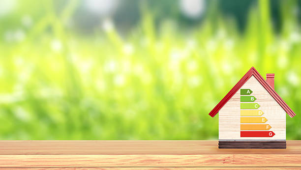 istock Energy efficiency chart on eco friendly house. Ecology, go green, environmental and conservation protection, energy class, bio energetic concept. Wooden toy home on wood tabletop outdoors in a forest 2207210841