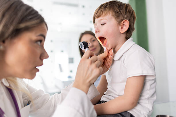 istock Pediatrician examining a little boy's throat 2207215082