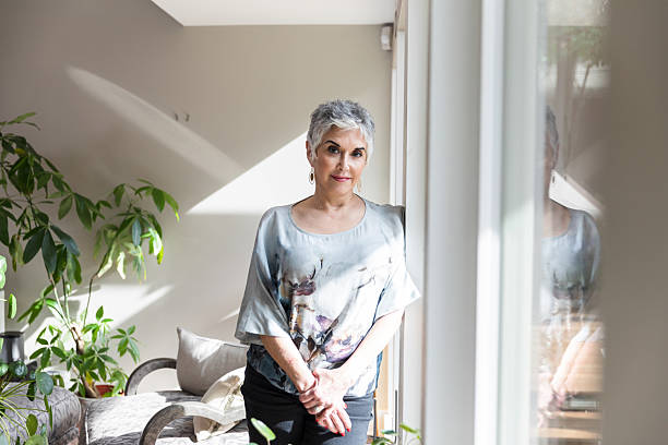 istock Confident Mature Woman Standing by Window in Home 2207220271