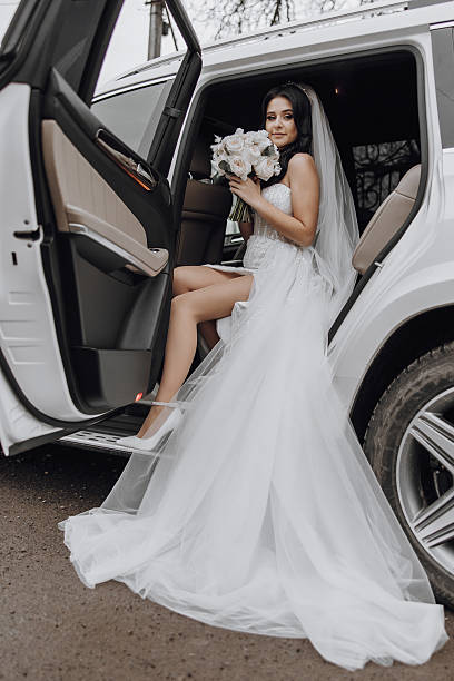 istock A bride is getting into a white car with a bouquet of flowers 2207221052