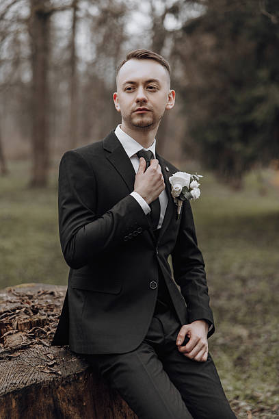 istock A man in a suit and tie sits on a log in a forest 2207221197