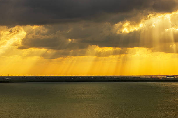 Golden sun rays breaking through dramatic storm clouds over calm Caribbean Sea at sunset. Mexico.