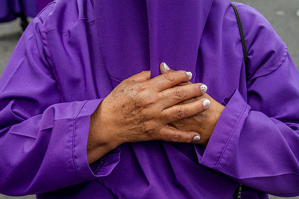 Quito, Pichincha, Ecuador - April 15, 2022: Close-up of a devoted woman's hands clasped over her chest in reverence during the Jesus del Gran Poder procession, a key event of Holy Week in Quito, Ecuador