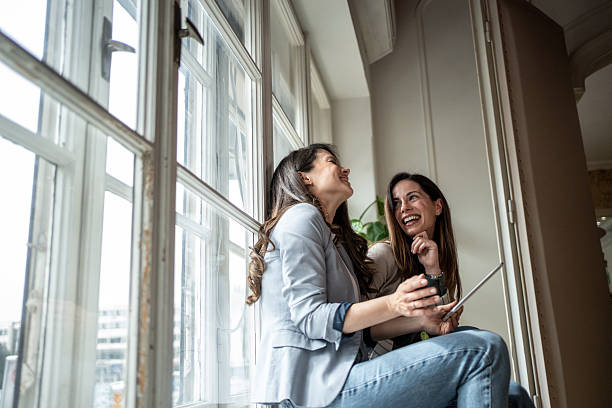 istock Two businesswomen sharing a laugh while using a tablet by the window 2207226662