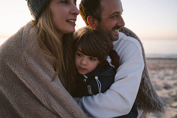 Portrait of a young family, having a picnic on the beach by the ocean