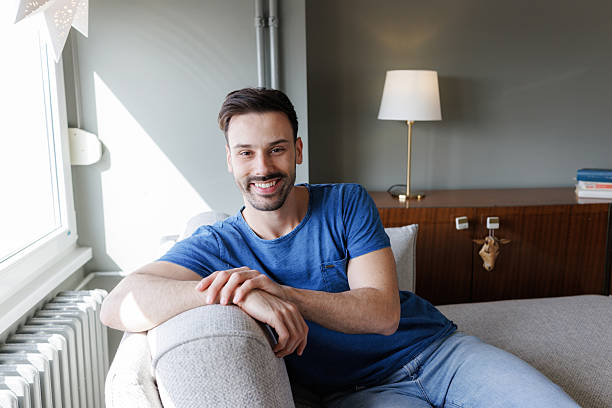 istock Smiling man relaxing on a couch in a living room 2207229197