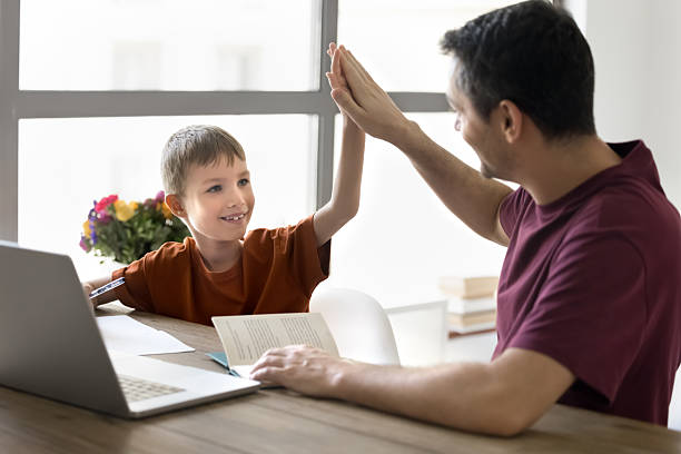 istock Happy schoolkid son and dad giving high five at home 2207233736