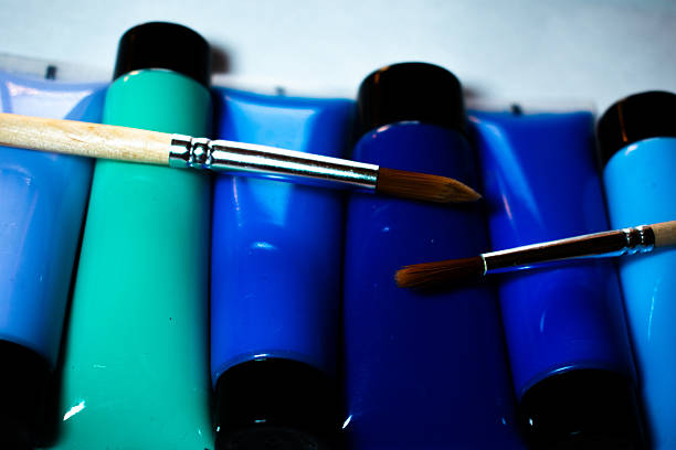 Blue paint can with brush on blue background in portrait format