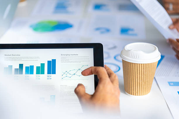 istock Close up of a business man using a digital tablet. There are finance charts, graphs and data on the screen 2207240170