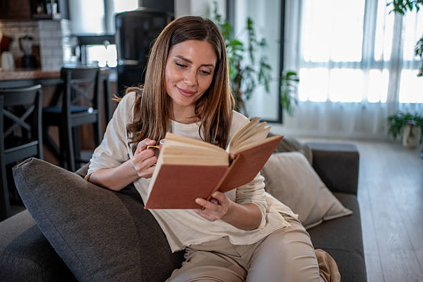 istock Woman relaxing on sofa reading a book and drinking tea 2207240465