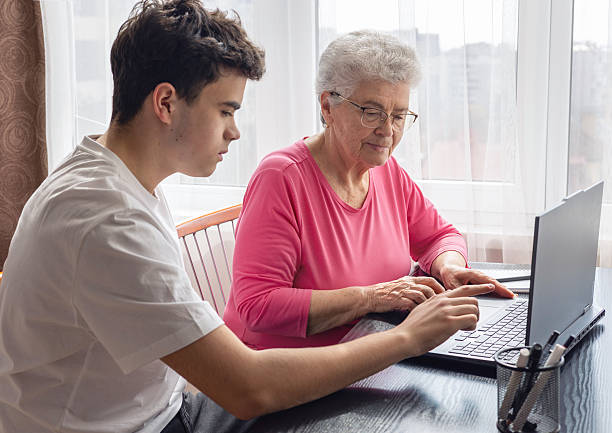 istock Grandson helping grandmother with computer, teaching digital skills, elderly woman learning technology, family support, intergenerational communication, senior education, online learning assistance. Digital literacy for seniors 2207241217