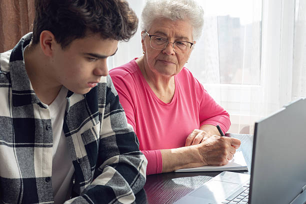 istock Grandson helping grandmother with computer, teaching digital skills, elderly woman learning technology, family support, intergenerational communication, senior education, online learning assistance. Digital literacy for seniors 2207241224