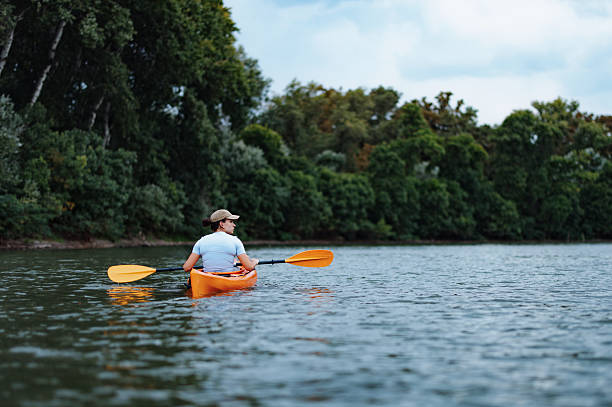 istock Person Kayaking on a Scenic River Surrounded by Lush Green Trees 2207242190