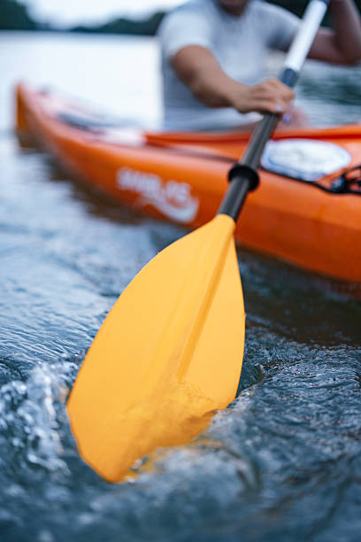 istock Person Kayaking on River with Yellow Paddle Creating Splashes in Water 2207242219