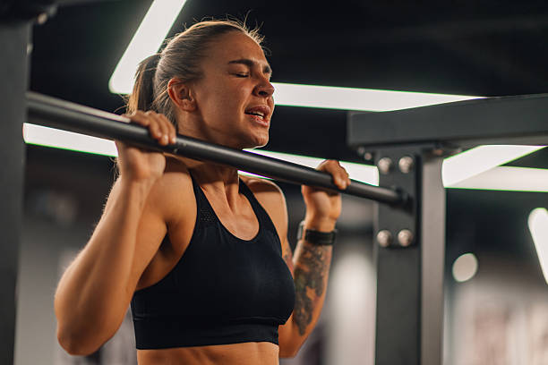 istock Determined young woman performing pull-ups in modern gym 2207242650