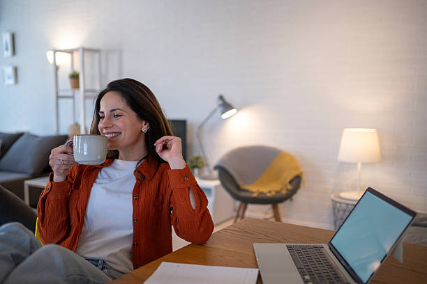 istock Happy woman drinking coffee while working from home 2207244066