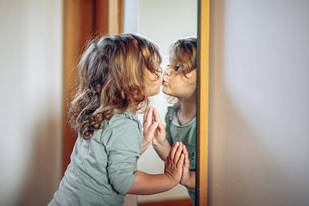 Little girl kissing her reflection in mirror