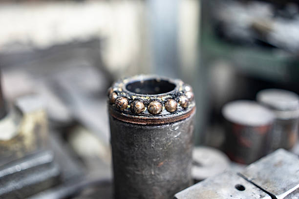 Detailed view of a metallic welding joint featuring spherical patterns. The industrial workshop background adds a technical and utilitarian context.