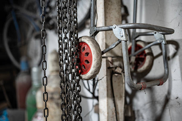 A detailed view of cart wheels with red hubs and suspended chains in an industrial setting, emphasizing mechanics and storage.