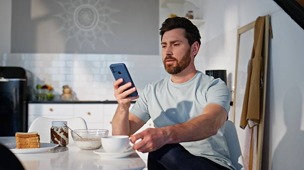 Morning man texting mobile phone sitting with coffee cup closeup. Relaxed guy