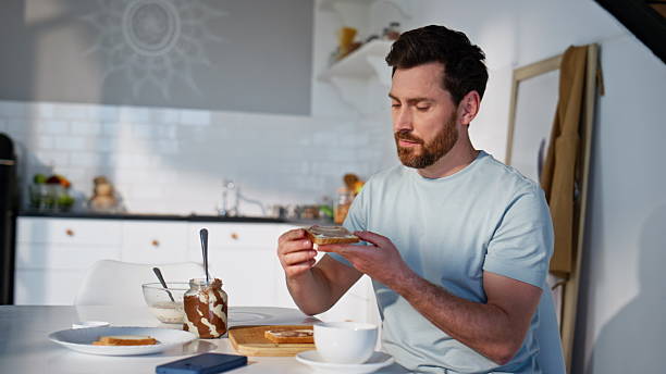 istock Breakfast guy making sandwich at light kitchen closeup. Hungry man eating snack 2207249912