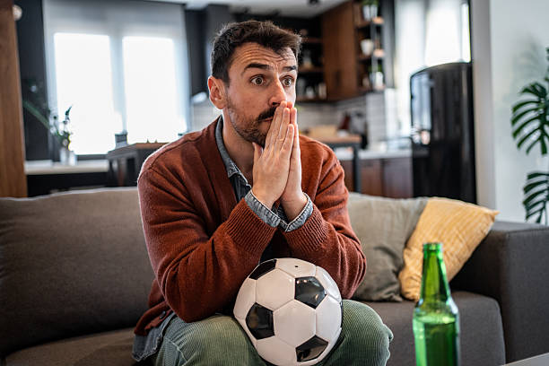 istock Worried football fan watching a match at home 2207250310