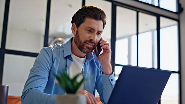 istock Happy businessman calling mobile phone at light home closeup. Freelancer talking 2207250930